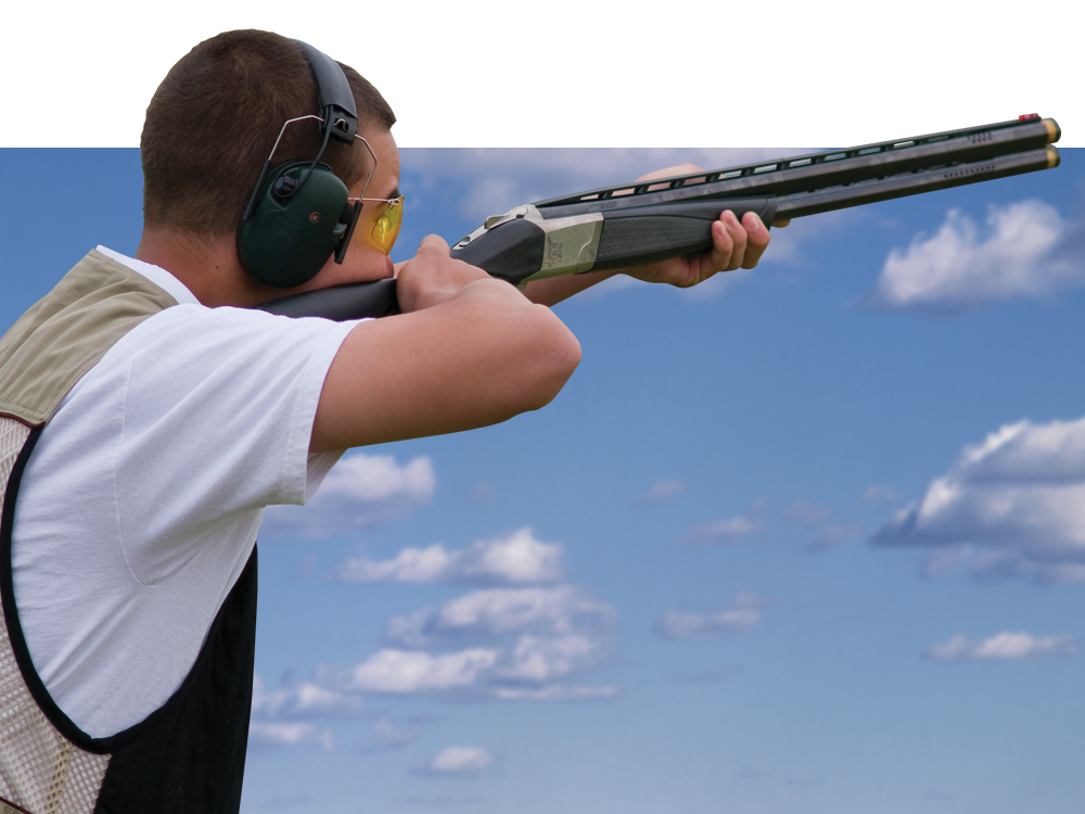 A man with a shotgun aiming at the sky.